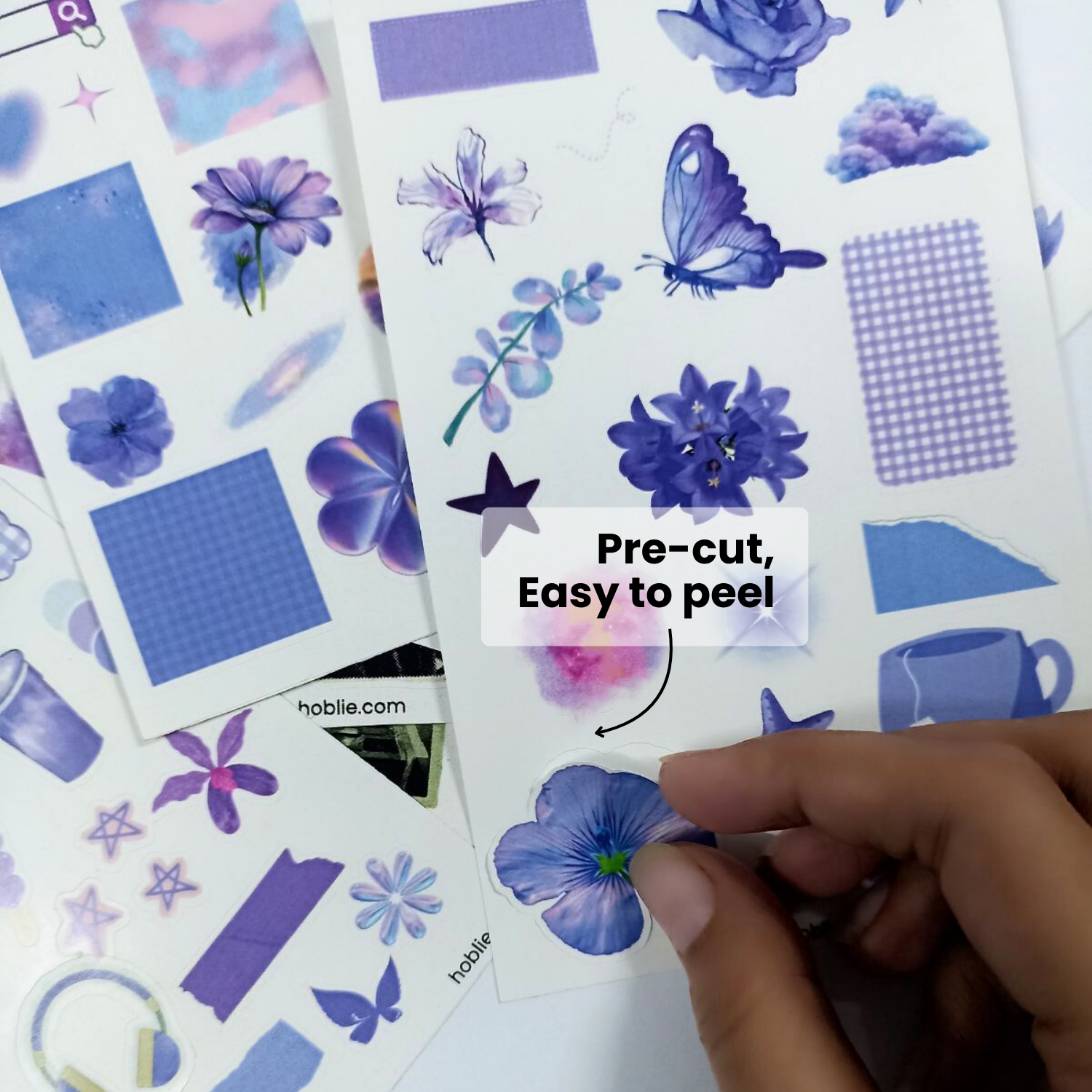Sticker sheets with blue floral and geometric designs, featuring a hand peeling a sticker.