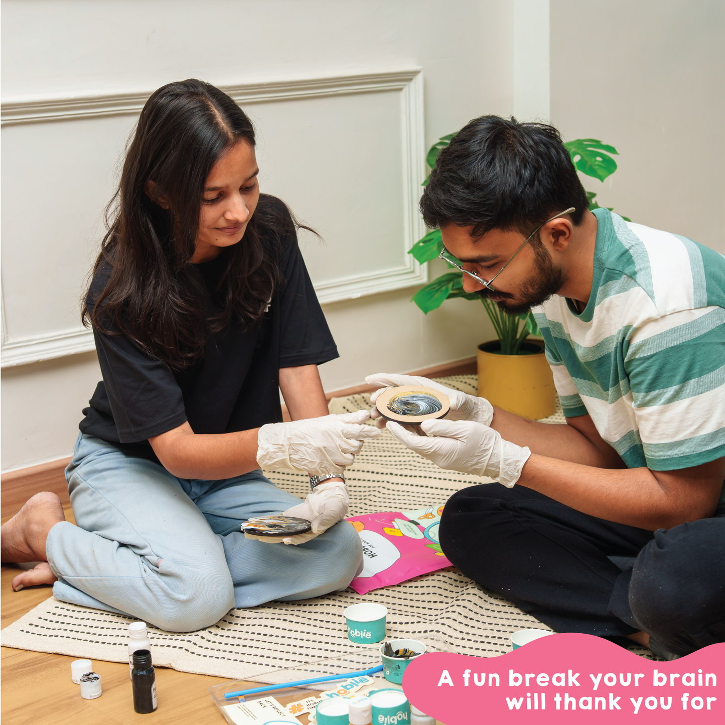Two people sitting on the floor with fluid art coaster painting kit,  doing a creative activity to give brain a fun break. The best DIY Kits for Adults - india.