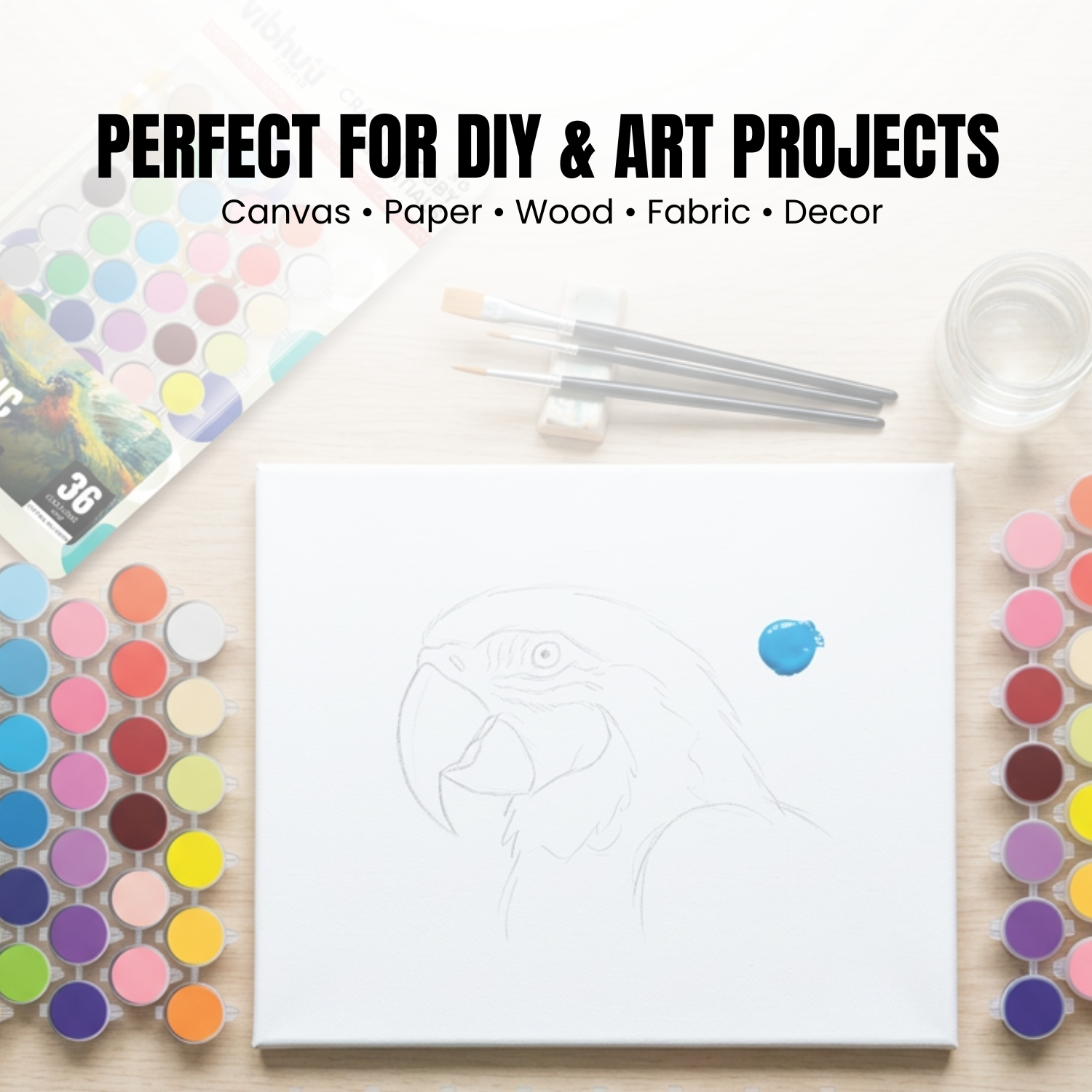 Art supplies including paint, brushes, and a canvas with a design on a white background.